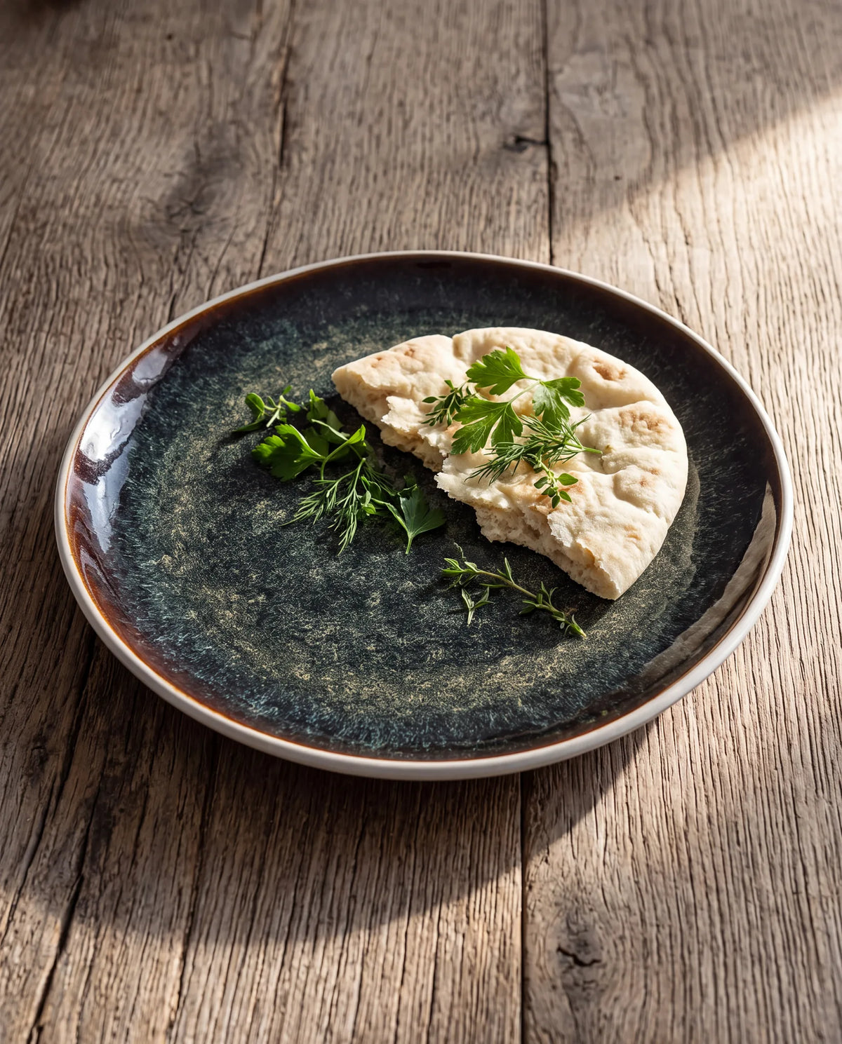Elite bord met plat brood en verse kruiden op eikenhouten tafel