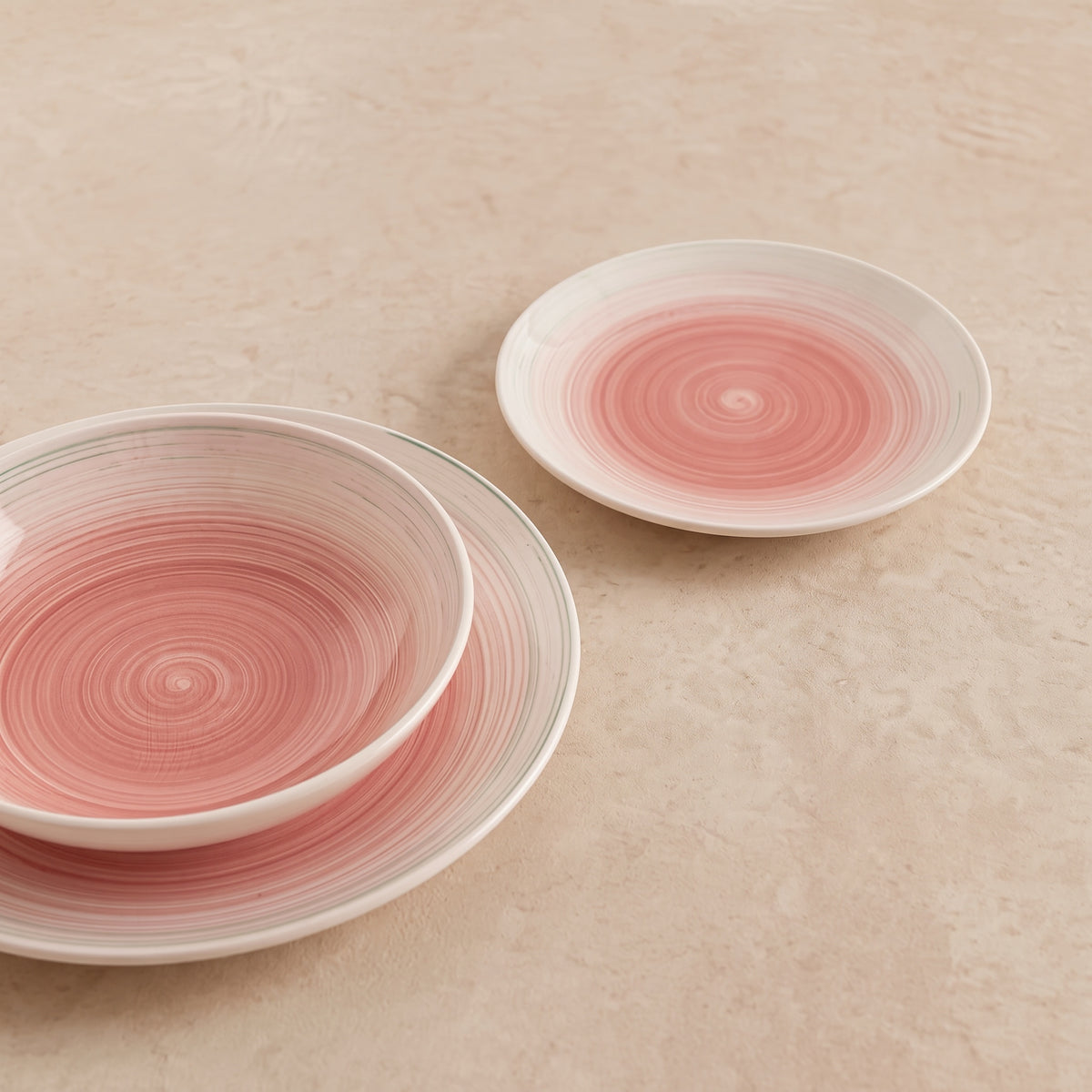 Velvet serviesset van drie roze handgeschilderde borden op een beige tafel