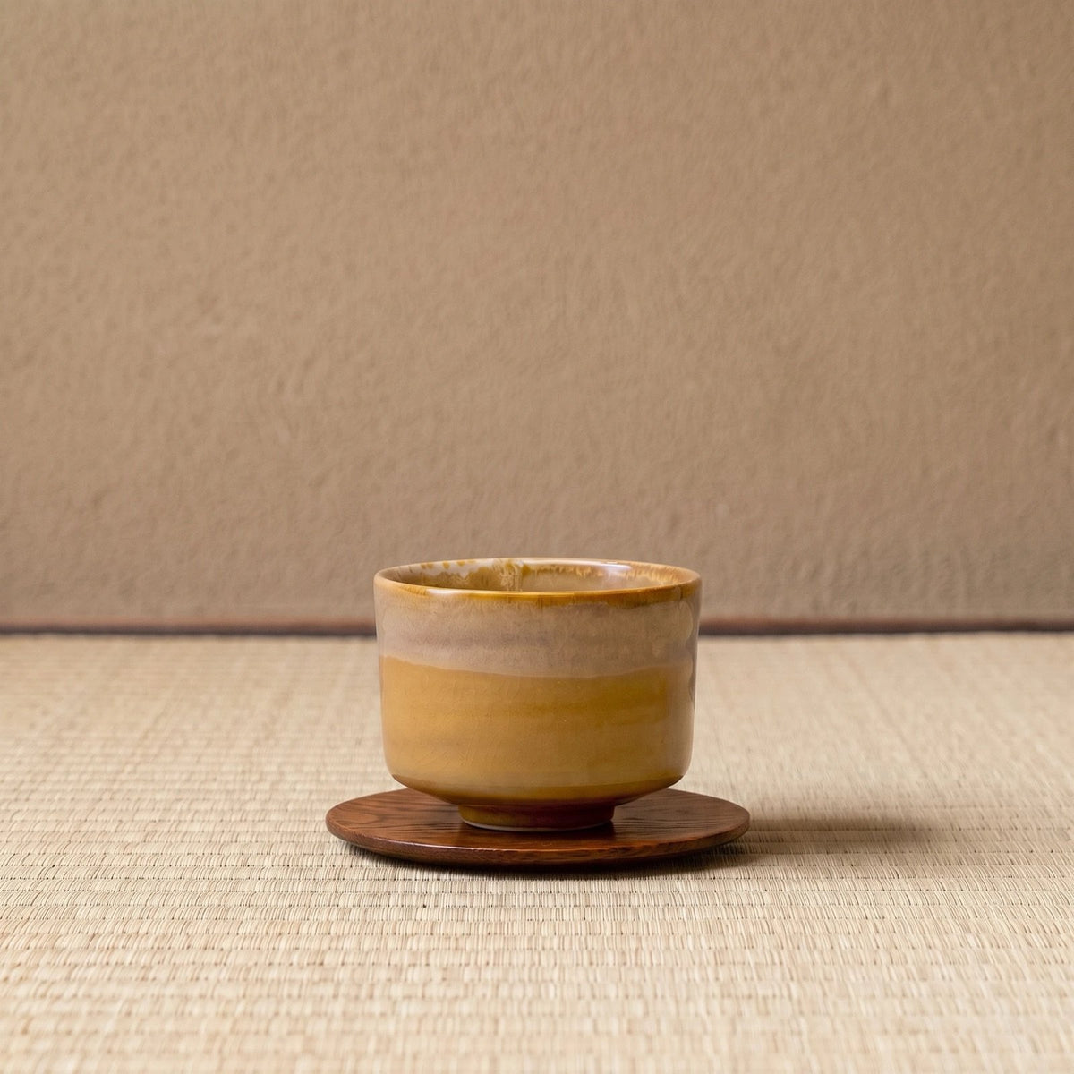 Caramel koffiekop op een houten onderzetter, op tatami voor een leemwand