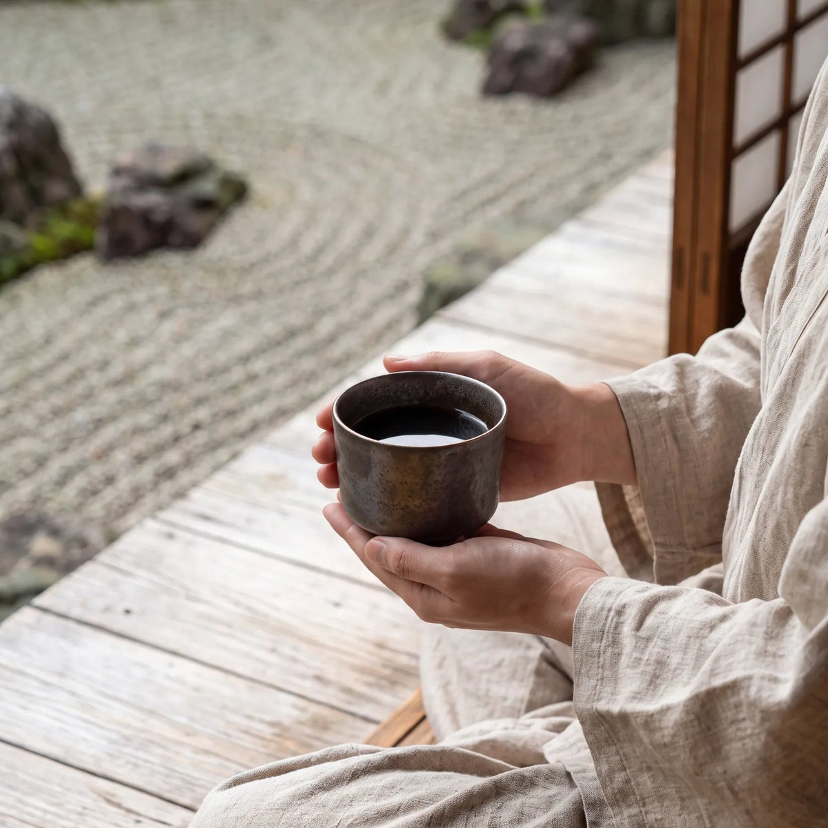Eclipse koffiekop vastgehouden met twee handen, bij een Japanse zentuin
