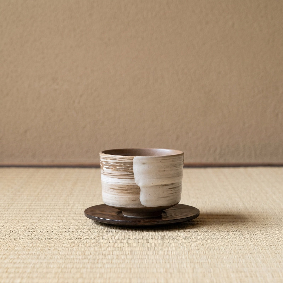 Swept Earth koffiekop op een houten onderzetter, op tatami voor een leemwand