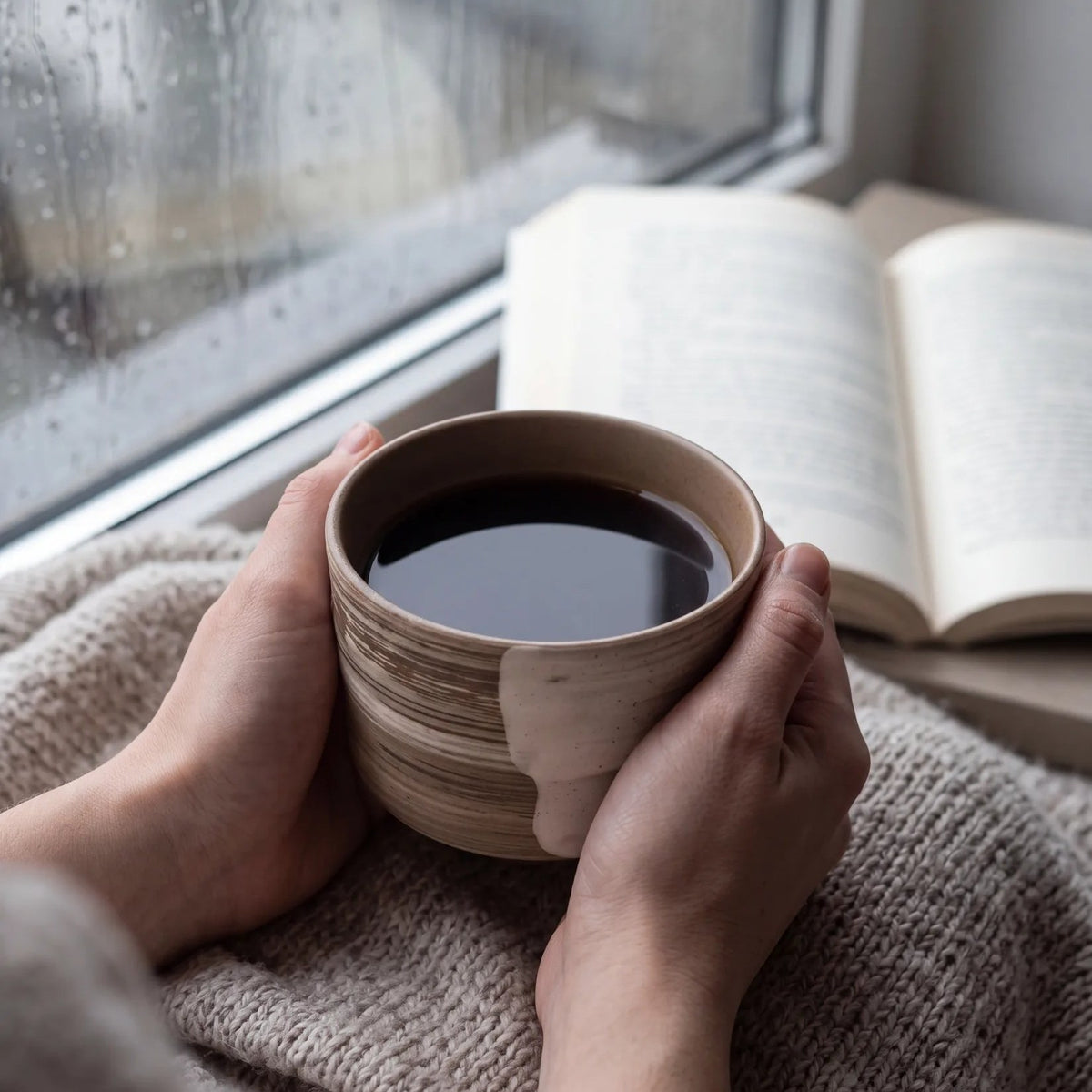 Swept Earth koffiekop in twee handen op een wollen deken